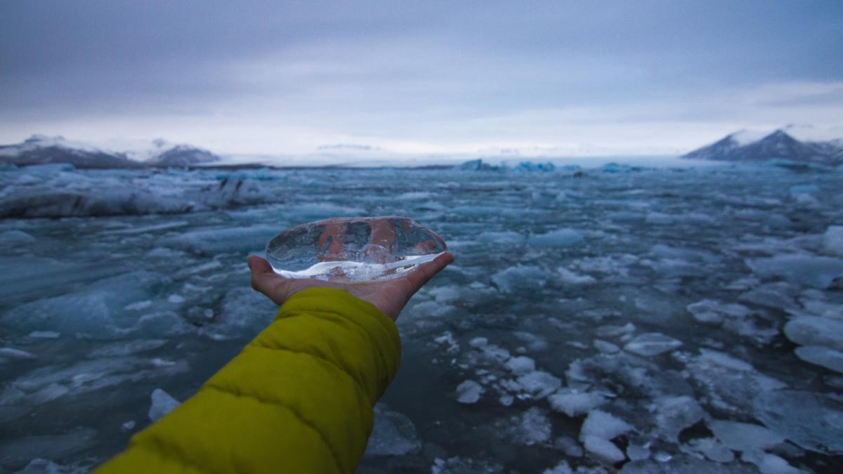 Рука, держащая лед с замерзшим морем