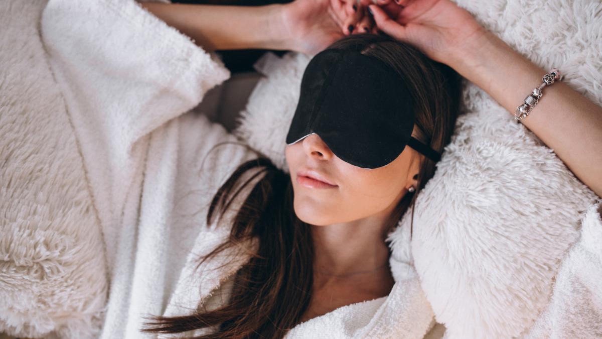 Женщина в кровати с маской для сна