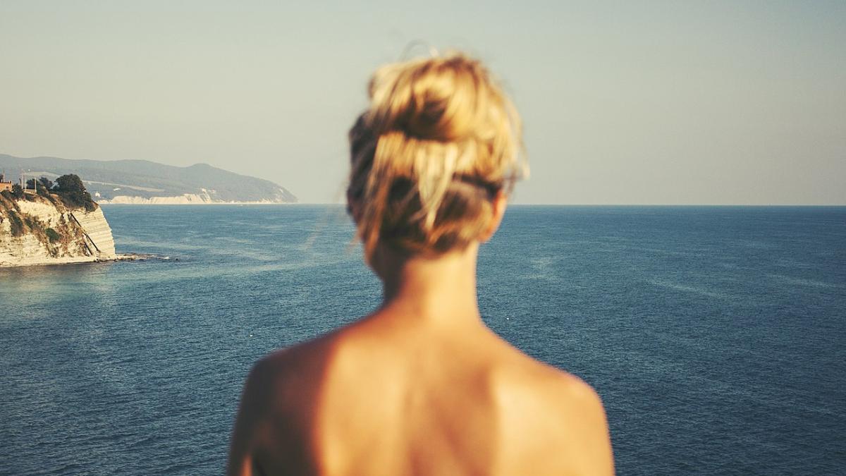 Девушка с голой спиной, смотрящая на море