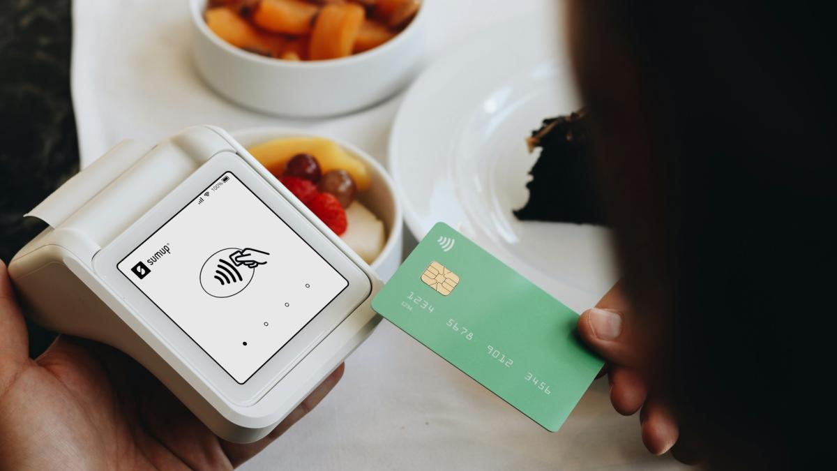 Человек прикладывает пластиковую карту к POS-терминалу