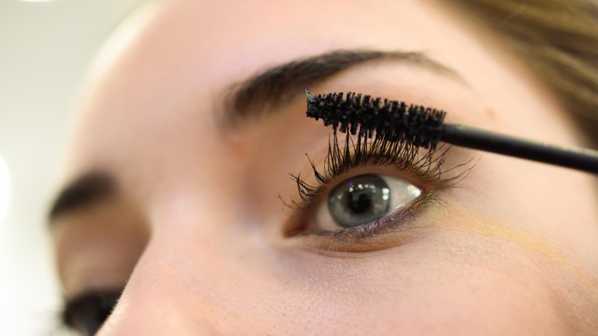 Крупный план глаз: нанесение черной туши на ресницы