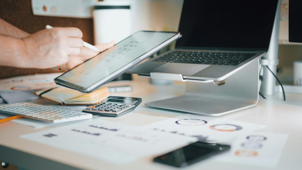 Рука указывает на растущий финансовый график на планшете