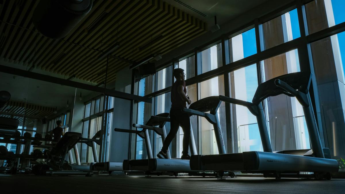 Занятия в тренажерном зале (человек на беговой дорожке)