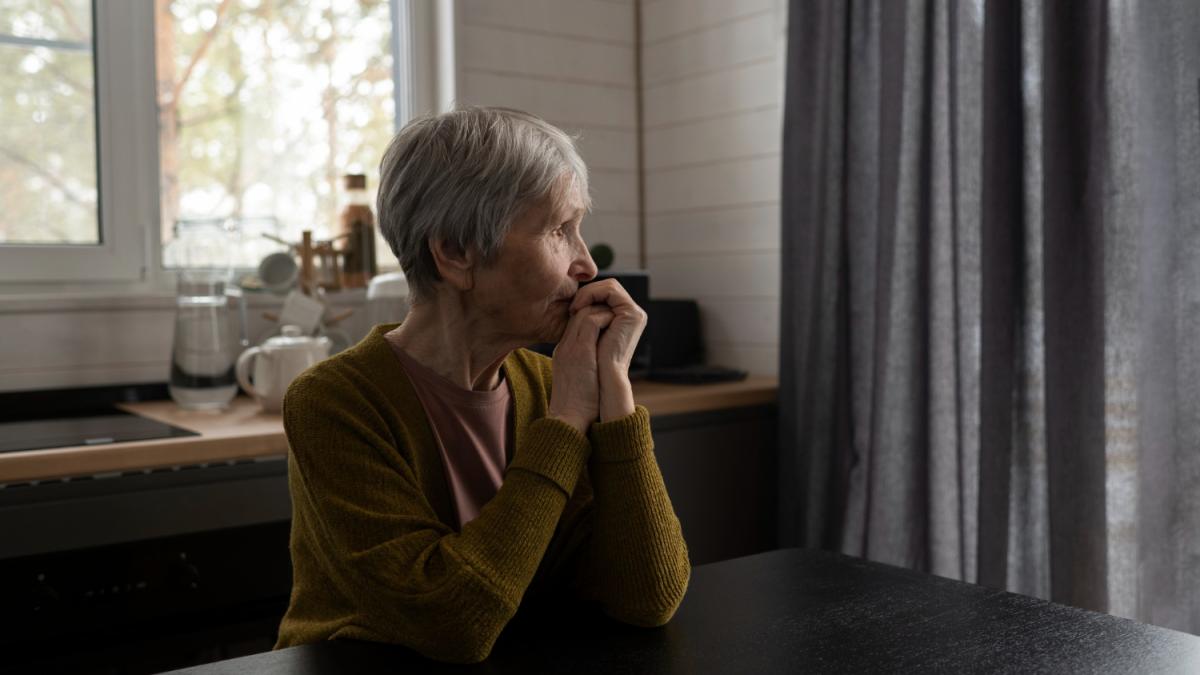 Пожилая женщина смотрит в окно