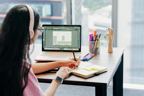 Девушка в наушниках работает за ноутбуком