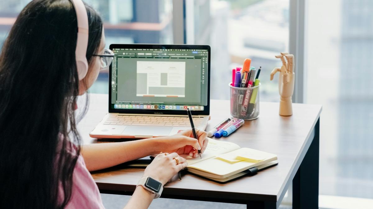 Девушка в наушниках работает за ноутбуком