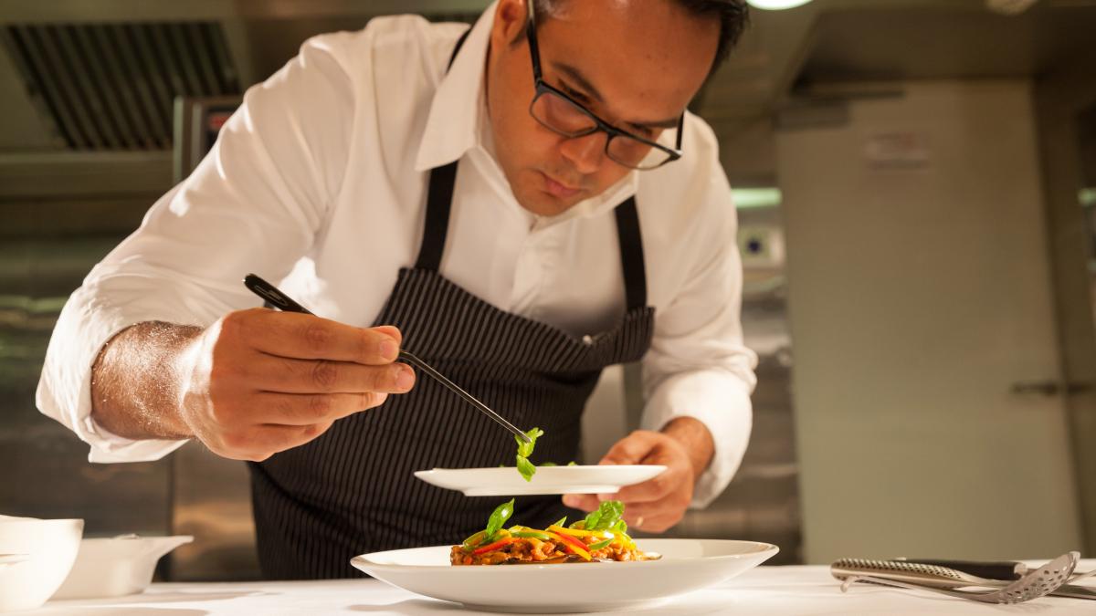 Шеф-повар в ресторане в процессе приготовления блюда