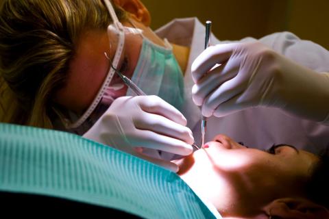 Стоматолог осматривает рот пациента