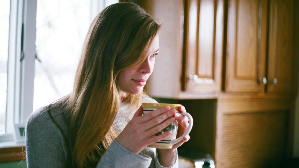 Женщина с чашкой кофе у окна