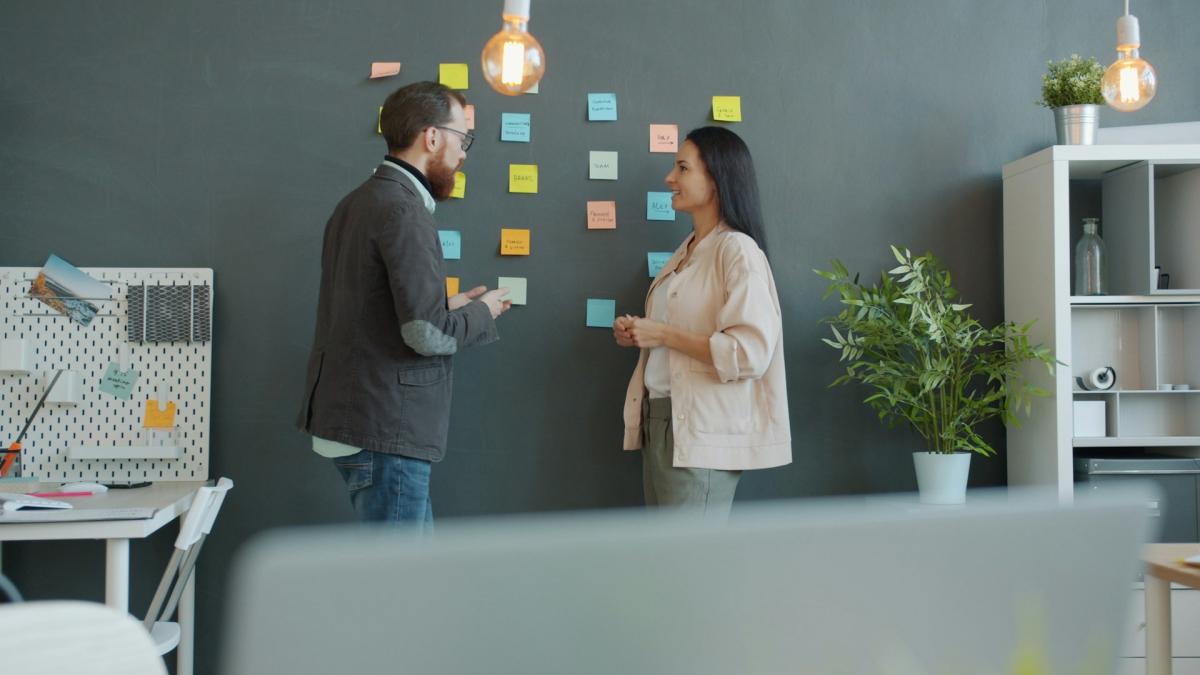 Сотрудники проводят мозговой штурм у белой доски со стикерами