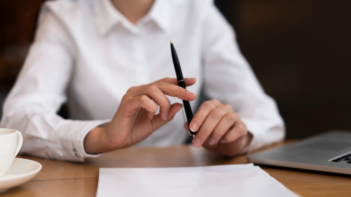 Женщина в белой блузке подписывает документы