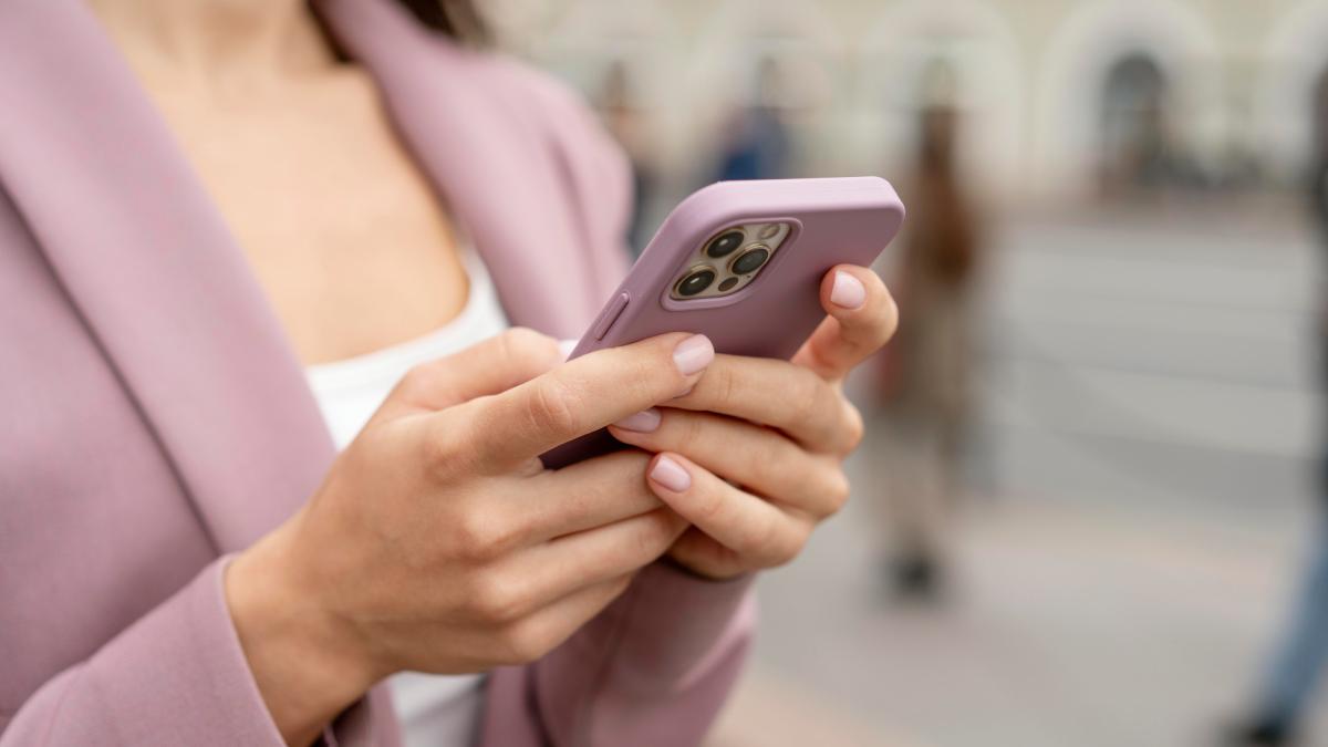 Женщина в розовом держит в руках розовый телефон