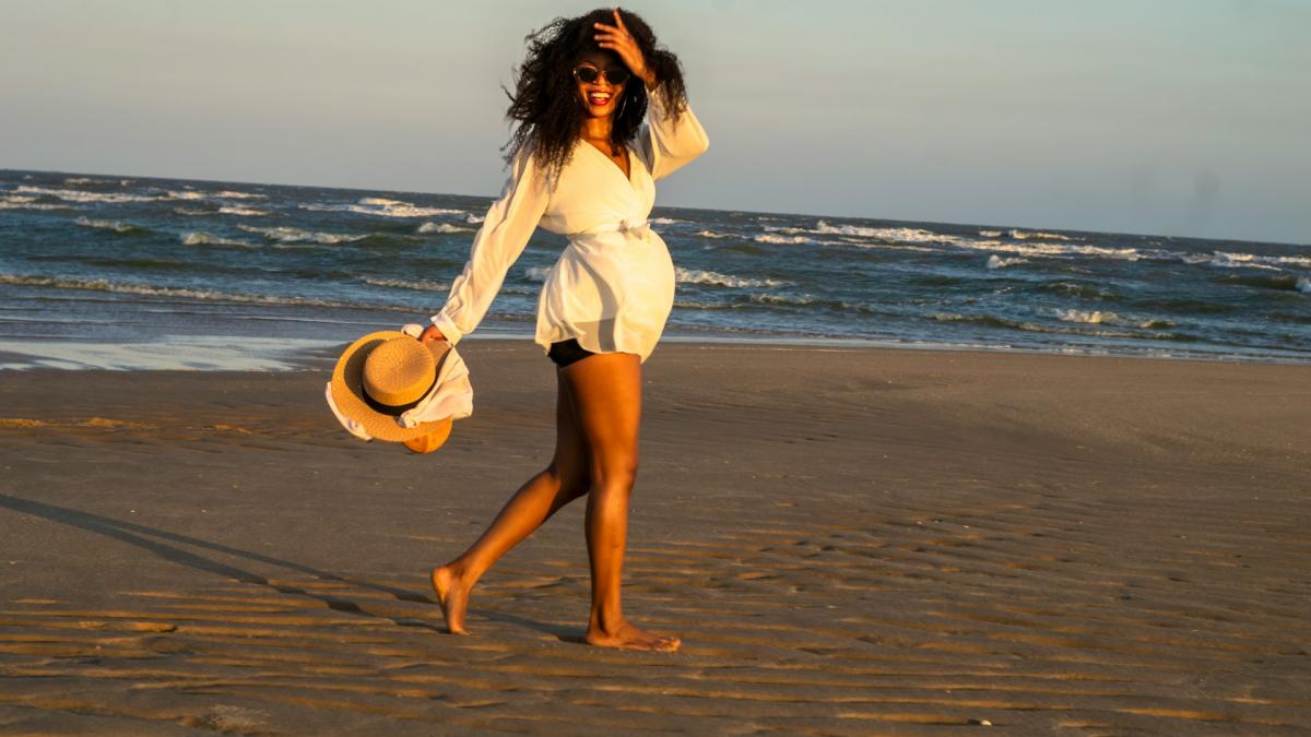 Женщина на пляже со шляпой в руке